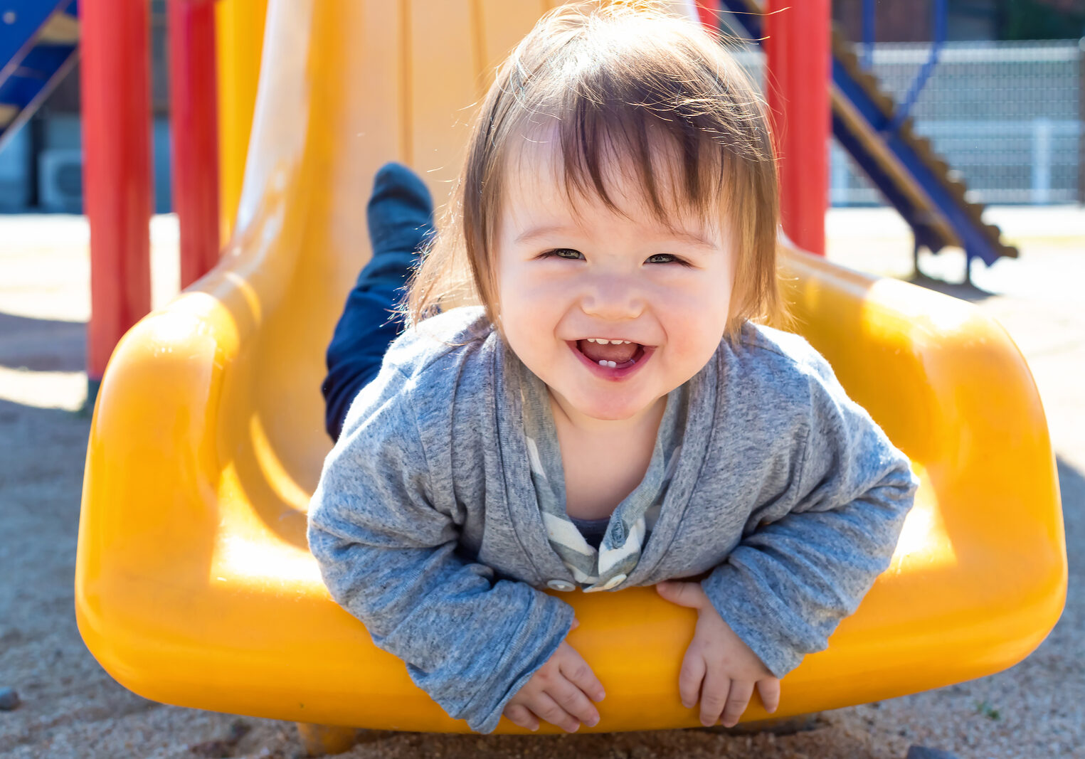 Mixed race toddler boy playing on a slide at a playground